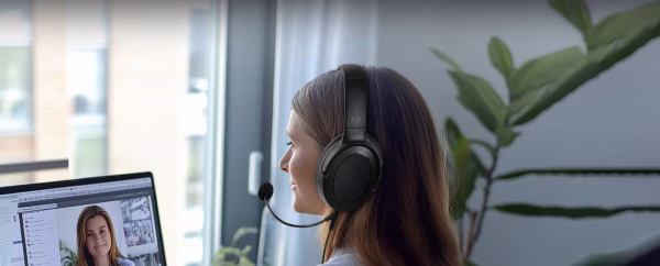 Una persona in un ufficio domestico indossa le cuffie Muse M-212 CH mentre partecipa a una videoconferenza sul suo laptop, con un'espressione professionale e concentrata."