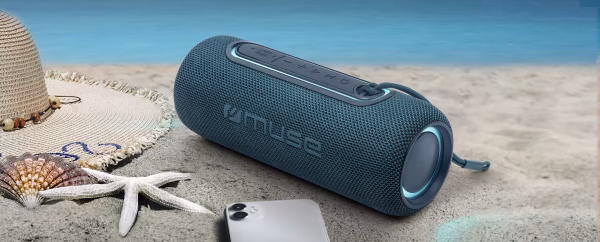 o speaker M-780 BTB su un tavolo a bordo piscina con alcune gocce d'acqua sulla superficie in tessuto, a dimostrazione visiva della sua resistenza agli spruzzi IPX4."